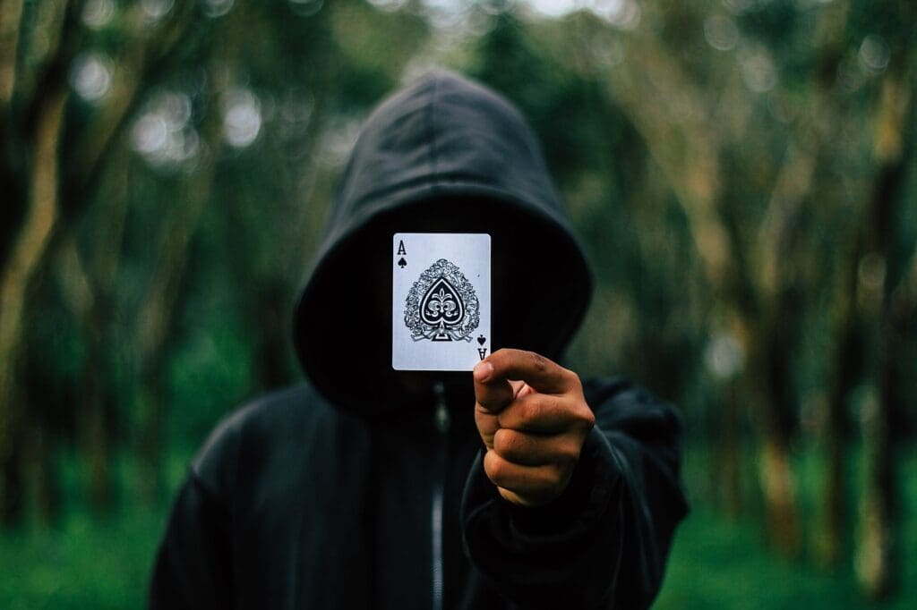 hooded man holding an ace